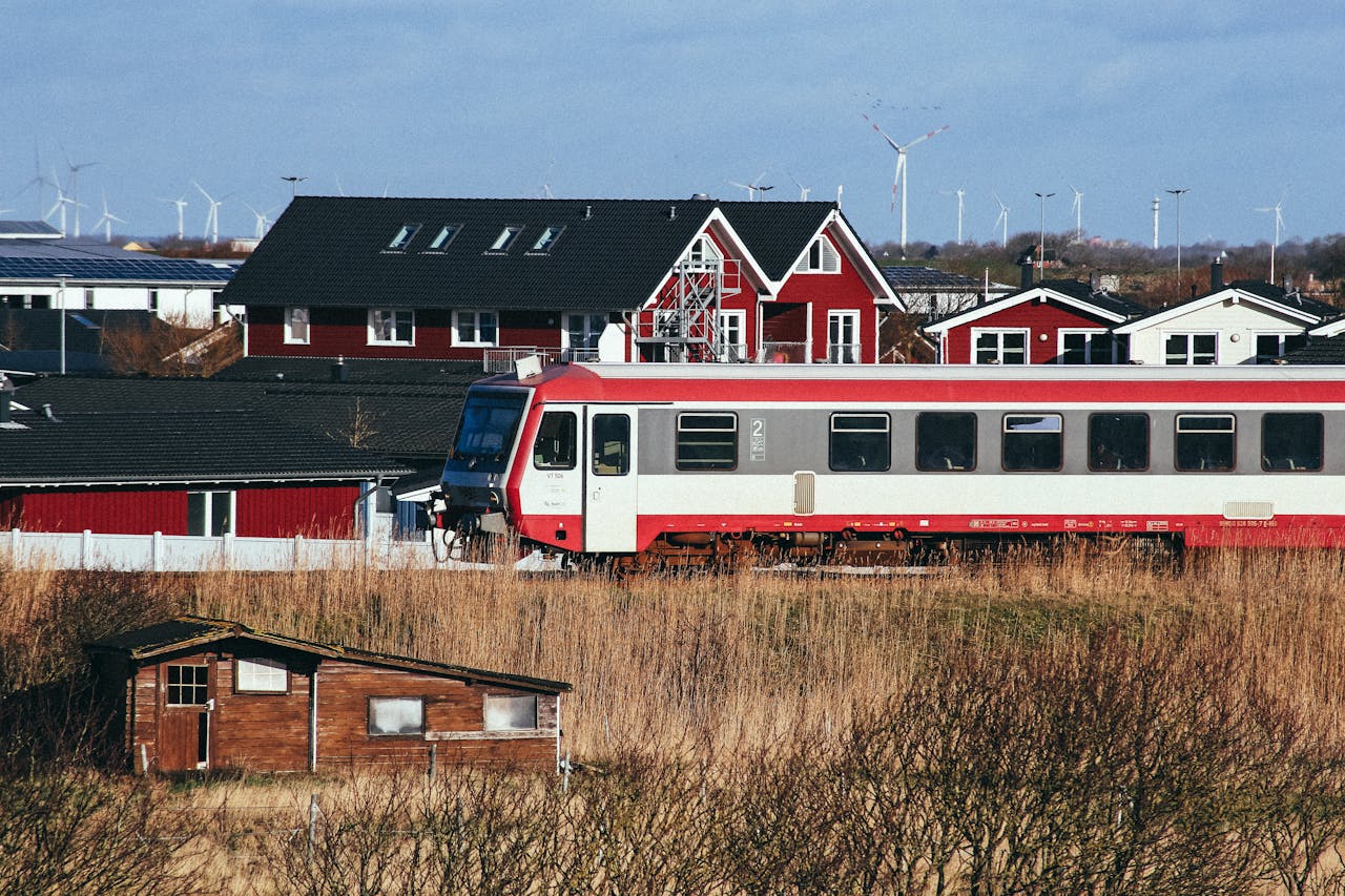 Scenic view of a train passing red houses and wind turbines in Dagebüll, Germany.